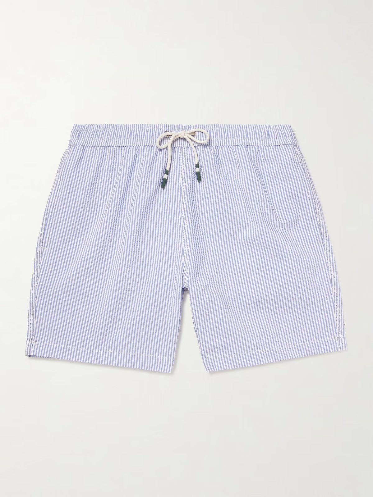 A person wears HARTFORD - SEERSUCKER SWIM TRUNKS IN INDIGO with a drawstring waist, side pockets, and a quick-drying seersucker fabric. The mid-thigh trunks are shown against a plain background, displaying only the torso and legs.