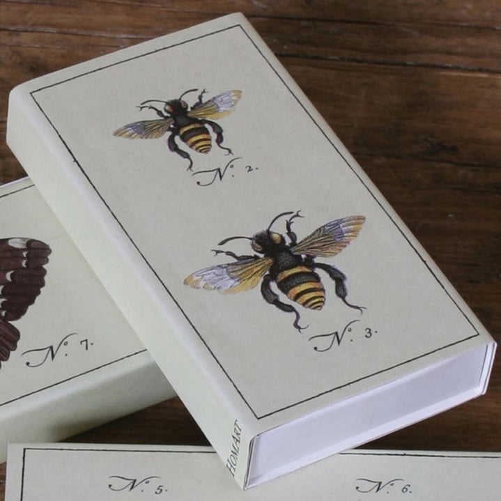 The HOMART MATCHES - BEES box contains yellow-tipped safety matches and features a vintage bee illustration on the box, with three labeled bees on an enclosed card—making it a delightful and charming hostess gift.