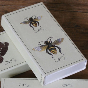 The HOMART MATCHES - BEES box contains yellow-tipped safety matches and features a vintage bee illustration on the box, with three labeled bees on an enclosed card—making it a delightful and charming hostess gift.