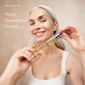 A smiling woman with long gray hair holds a bottle of ELEMIS - PRO-COLLAGEN TONING MIST by ELEMIS - STEINER, a hydrating toning mist formulated to refine the skin. Text on the image reads: “KEY BENEFITS: Preps, Replenishes, Refines.” She is wearing a white tank top and stands against a neutral background.