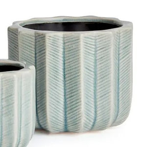 The NAPA HOME AND GARDEN - VELA POT, LARGE by NAPA HOME AND GARDEN features a fully visible ceramic planter with a light blue chevron pattern and textured vertical ridges, forming part of a charming decorative set. A smaller matching pot is partially displayed in the foreground on the left.