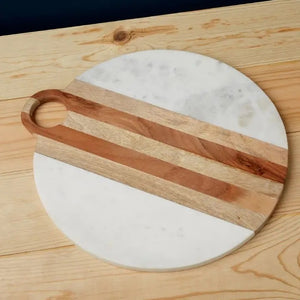 The BE HOME - MOA Marble & Wood Round Board by BE HOME, INC is handmade in India, featuring a central wooden stripe on white marble and finished with a circular top handle.
