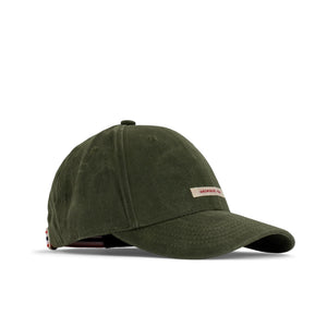 The AMUNDSEN SPORTS - WAXED COTTON CAP in navy blue is shown from the side against a plain white background, featuring a curved brim and an adjustable strap with a red, white, and black checkered norgesreima design.