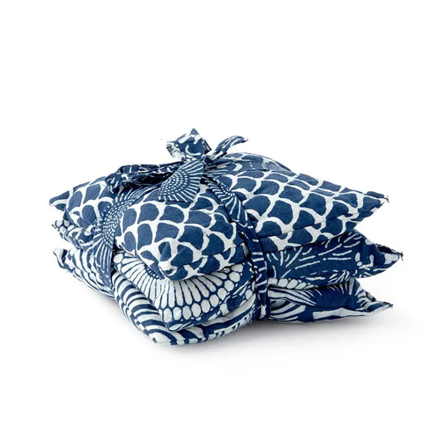 Three square pillows in blue and white patterns—a geometric wave, a radial fan motif, and circular flower-like shapes adorned with leafy details—ideally complement the use of BAUDELAIRE&#39;s Chamomile Sleep Sachets by infusing relaxation into your sleep sanctuary.