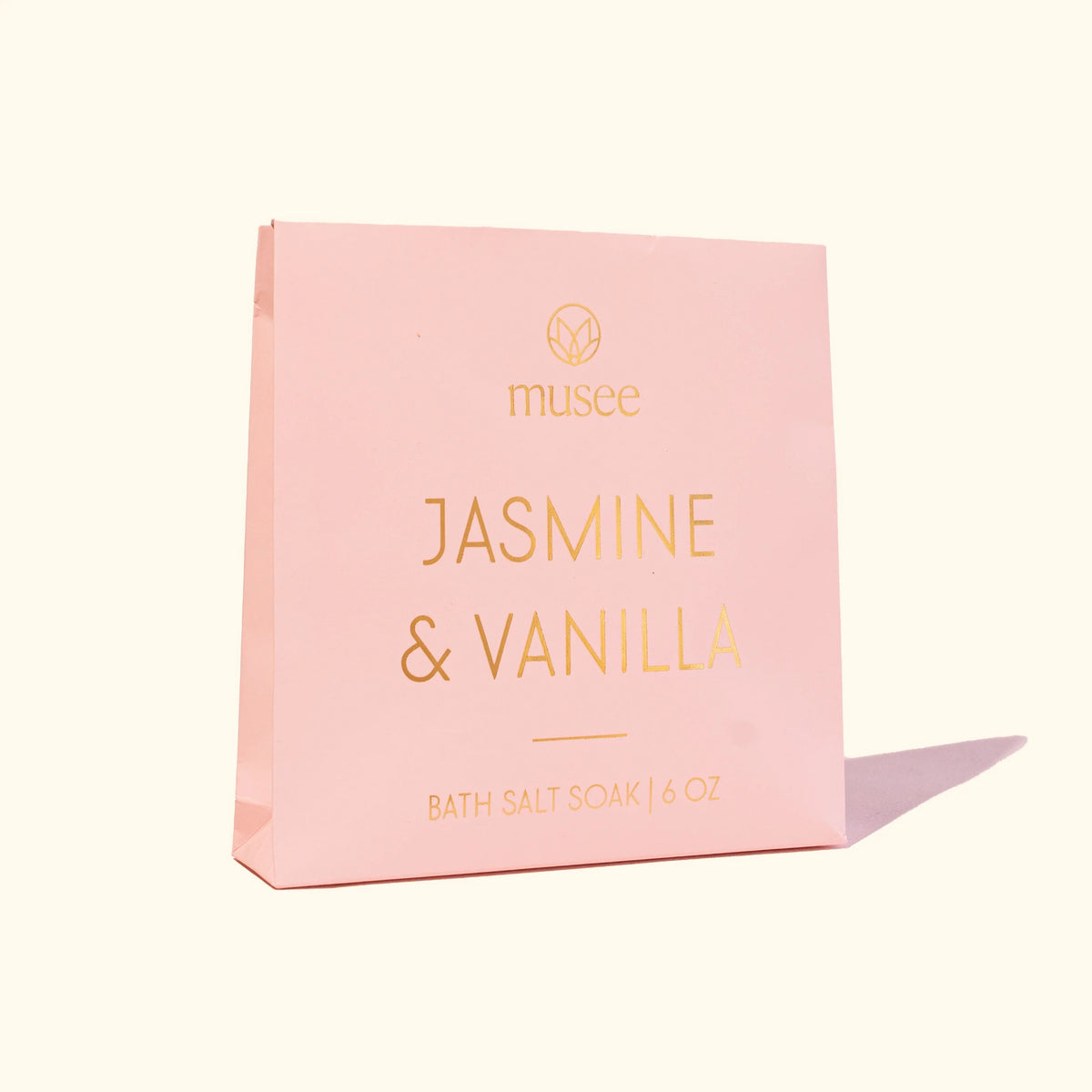 A pink package labeled “MUSEE - JASMINE & VANILLA MINI BATH SALT SOAK” by MUSEE, with a small pile of white bath salts spilled next to it, highlights the soothing benefits of natural bath products. Relax and unwind as you enjoy the calming jasmine vanilla aroma in your Epsom salt bath for ultimate tranquility.