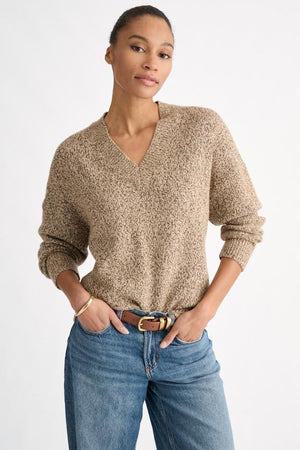 A person wearing the KINROSS CASHMERE Sequin Marle Easy Vee Neck Sweater in Scotch, paired with blue jeans and a brown belt, stands with hands in their pockets against a plain light background.
