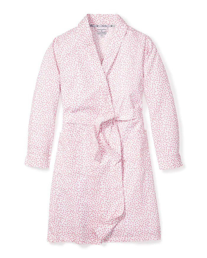 The PETITE PLUME - SWEETHEARTS ROBE by PETITE PLUME is a luxurious bathrobe that showcases a delightful small floral print pattern in pink and white. Crafted from the finest quality cotton, this elegant robe features long sleeves, a shawl collar, and a matching belt tied at the waist. The soft and comfortable fabric makes it perfect for lounging in style.