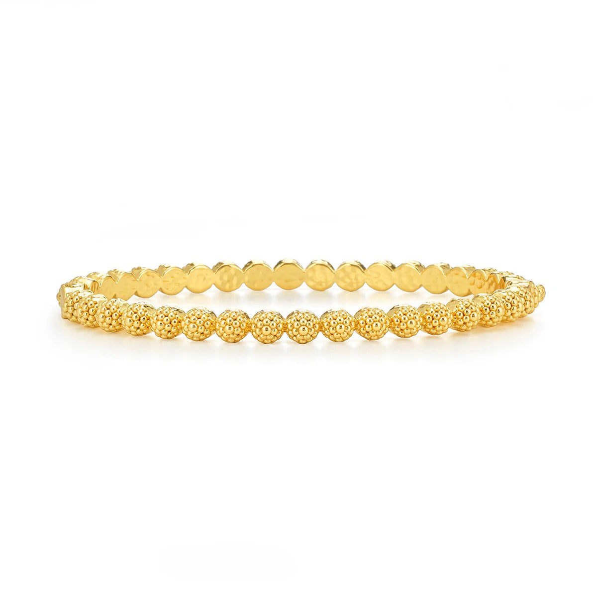 A woman with long blonde hair dons a white off-shoulder top and an 18K gold necklace featuring a pearl pendant. Her accessories include matching earrings and the CAPUCINE DE WULF BERRY ETERNITY PETITE HINGED BANGLE, all set against a backdrop of lush greenery.
