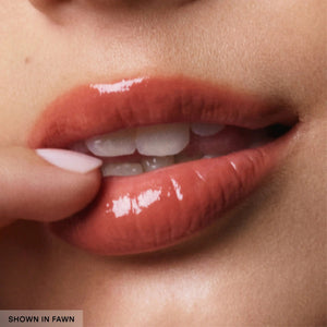 A small, light brown tube of UBEAUTY - PLASMA LIP COMPOUND IN FAWN by U BEAUTY, a luxe plumping collagen lip care balm, stands upright on a light gray background with product details printed in white.