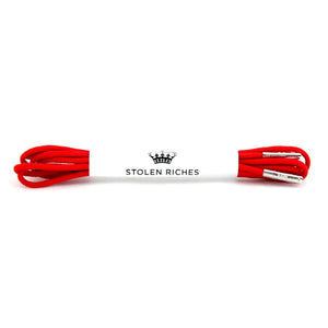 A pair of STOLEN RICHES Dress Shoelaces in Portsalon Red, neatly bundled with a white paper band featuring a crown logo and “STOLEN RICHES” in black.