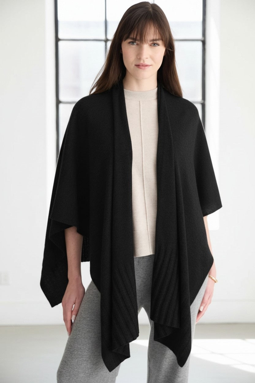 The KINROSS CASHMERE - CASHMERE RUANA IN BLACK by KINROSS is a luxurious, open-front wrap featuring a draped silhouette and subtly textured hem, showcased against a plain white background.