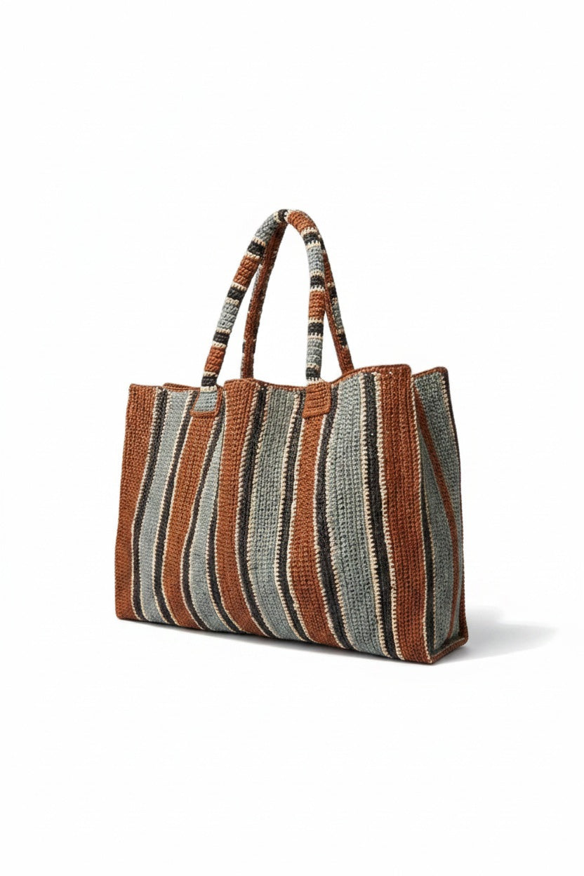 The GABRIELE FRANTZEN Raffia Weekender Bag Tobacco is a large, handmade bag with two handles and vertical stripes in brown, tan, cream, and gray for a textured, artisanal look.