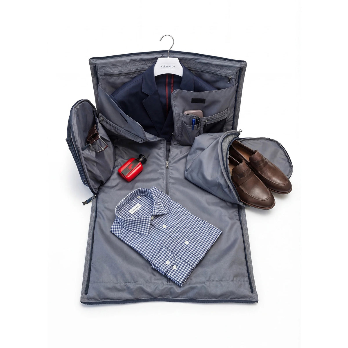 The COLLARS AND CO - GARMENT DUFFEL BAG by COLLARS AND CO rests on a tan leather seat in a private jet, alongside a passport, sunglasses, and notebook—your ideal organizer for effortless travel.