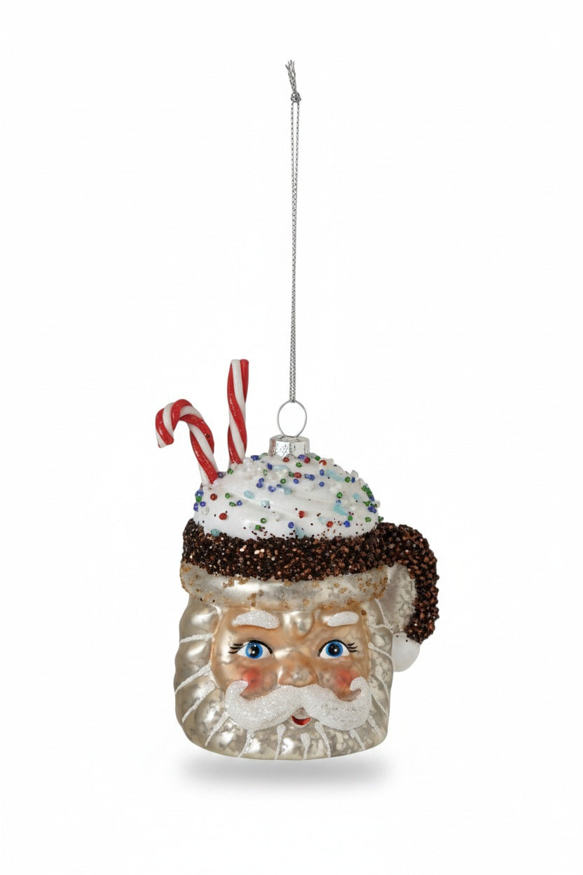 A CREATIVE COOP SANTA MUG ORNAMENT hand-painted and filled with whipped cream, colorful sprinkles, and a candy cane.