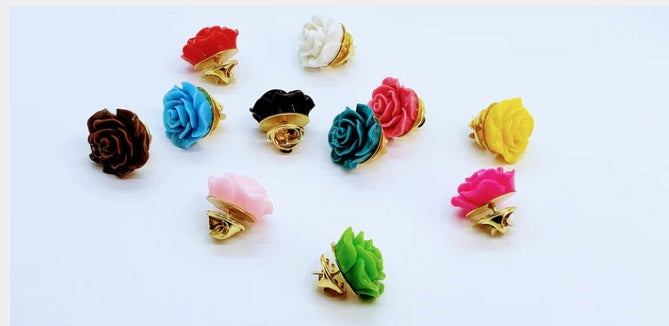 The CLIFTON WILSON - RESIN LAPEL FLOWER PIN IN PINK is a glossy, rose-shaped accessory with intricate petals, shown on a plain white background—a stylish formalwear piece by CLIFTON WILSON.