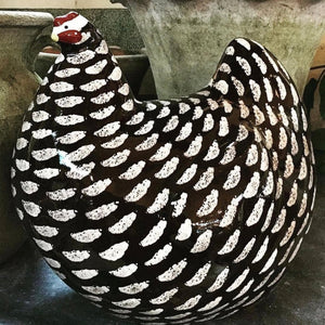 A LES CERAMIQUES DE LUSSAN large ceramic French pullet in black spotted white stands on a light-colored cylindrical base against a plain background.
