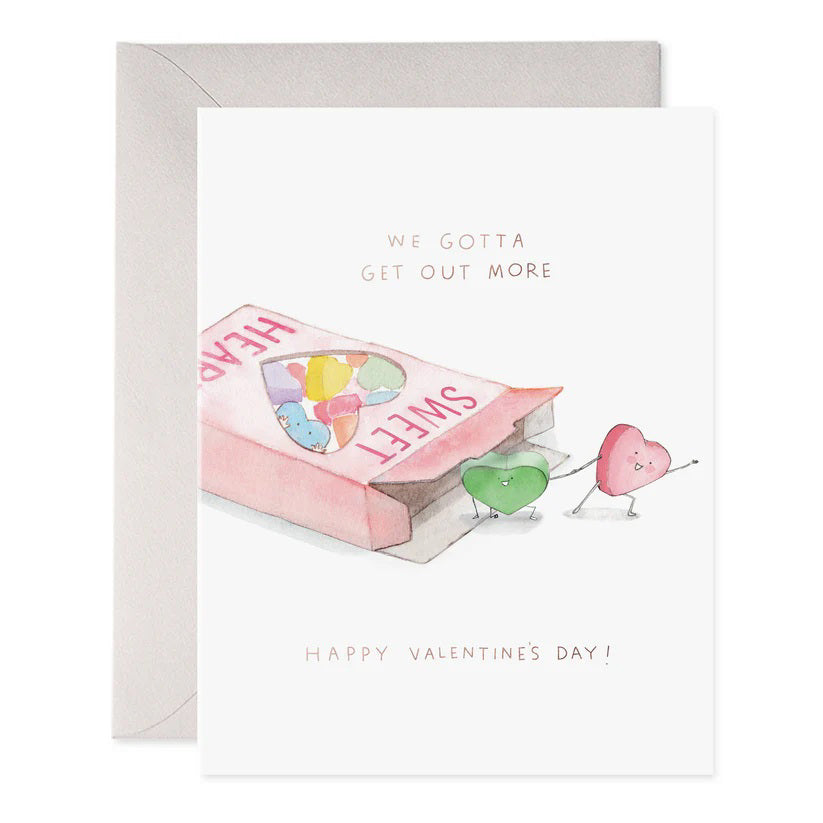 The "We Gotta Get Out More" greeting card by E. Frances Paper showcases a pink "SWEET HEARTS" candy box with two heart-shaped candies stepping out. Crafted on luxe heavyweight paper, it features the playful text above and gold foil elegance beneath with "HAPPY VALENTINE'S DAY.