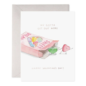 The "We Gotta Get Out More" greeting card by E. Frances Paper showcases a pink "SWEET HEARTS" candy box with two heart-shaped candies stepping out. Crafted on luxe heavyweight paper, it features the playful text above and gold foil elegance beneath with "HAPPY VALENTINE'S DAY.