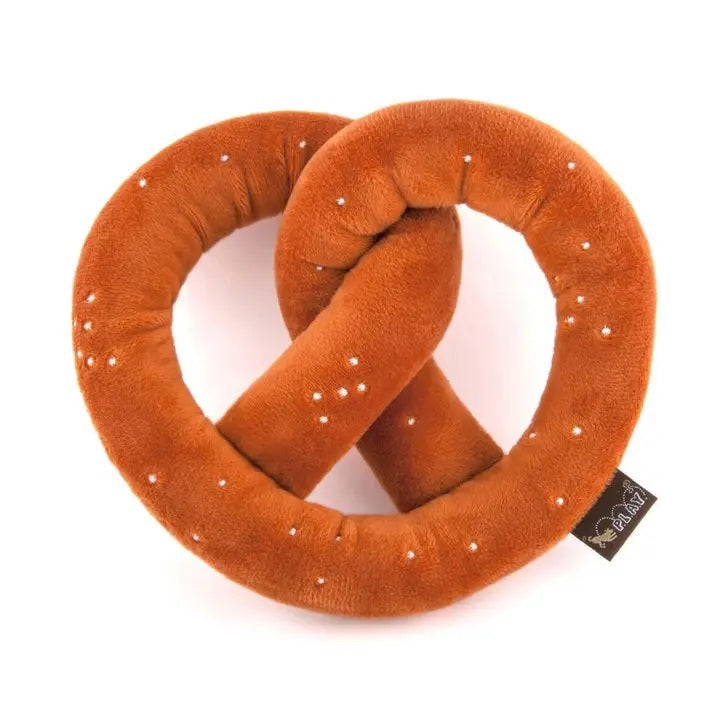 Introducing the INTERNATIONAL CLASSIC PRETZEL by PLAY PET LIFESTYLES/BRANDS – a soft, brown plush toy with white salt-like dots and a black tag, designed in the shape of a twisted pretzel. Perfect as an international food-themed dog toy for pups who love playful snacking fun!.