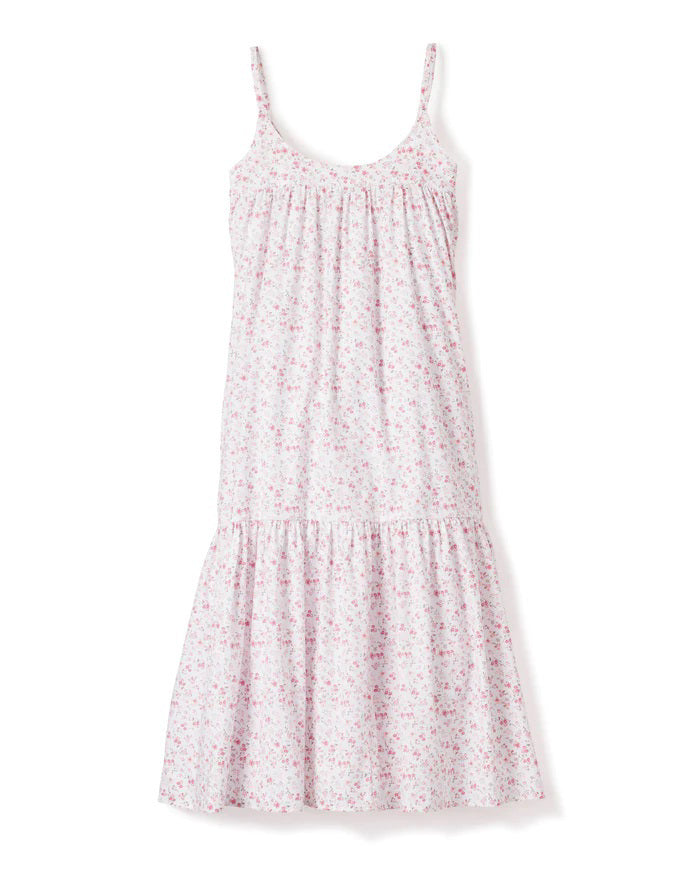 The PETITE PLUME - DORSET FLORAL CHLOE NIGHTGOWN is a sleeveless, white sundress with thin straps, reminiscent of luxurious sleepwear. It showcases a flowing, tiered design adorned with a delicate pink floral pattern. Made from the finest quality cotton, the fabric is lightweight and airy, perfect for warm weather. Displayed against a white background.