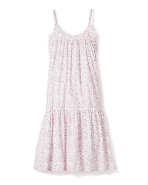The PETITE PLUME - DORSET FLORAL CHLOE NIGHTGOWN is a sleeveless, white sundress with thin straps, reminiscent of luxurious sleepwear. It showcases a flowing, tiered design adorned with a delicate pink floral pattern. Made from the finest quality cotton, the fabric is lightweight and airy, perfect for warm weather. Displayed against a white background.