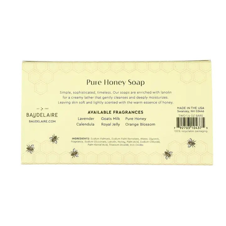 Two BAUDELAIRE soap boxes with floral designs, one opened to reveal a honeycomb patterned soap bar inside. Labels show 'Pure Honey' and 'Royal Jelly'. Text on the side reads "Crafted by Artisans. Cherished by You." The BAUDELAIRE - PURE HONEY SOAP 1.4OZ MATCHBOX DUO is the perfect gift for any occasion. Background is plain white.