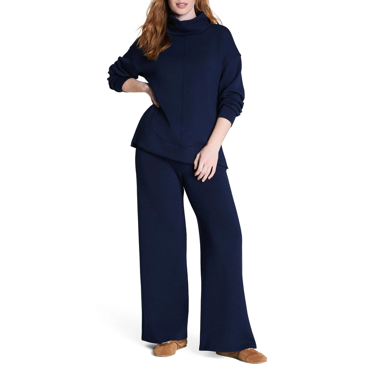 A woman in the SPANX AirEssentials Turtleneck Tunic in Timeless Navy displays a relaxed fit made with breathable spacer fabric for comfort.