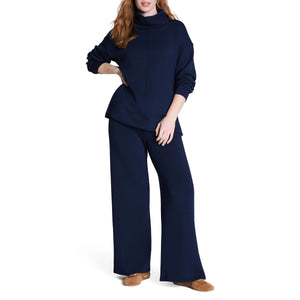 A woman in the SPANX AirEssentials Turtleneck Tunic in Timeless Navy displays a relaxed fit made with breathable spacer fabric for comfort.
