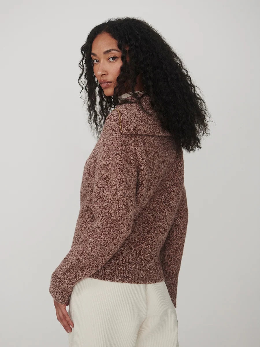 A person wearing a VARLEY - SHERIDA HALF-ZIP KNIT SWEATER IN GINGERBREAD FLECK, a brown speckled boucle yarn sweater with a collared half-zip neckline.