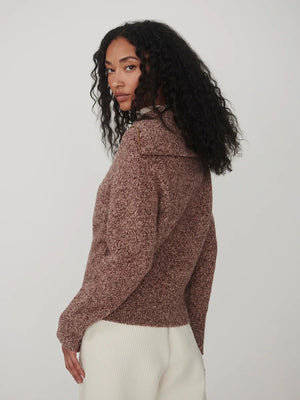 A person wearing a VARLEY - SHERIDA HALF-ZIP KNIT SWEATER IN GINGERBREAD FLECK, a brown speckled boucle yarn sweater with a collared half-zip neckline.