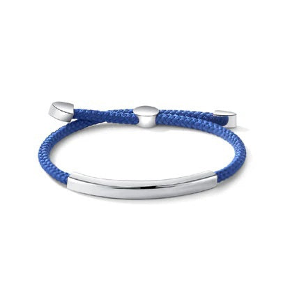 The STOLEN RICHES Algarve Bracelet features a blue nylon band, a curved silver bar, and silver end caps with an adjustable sliding clasp for a minimalist look.