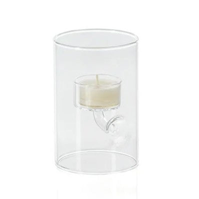 ZODAX SUSPENDED GLASS TEALIGHT HOLDER - EXTRA SMALL displays red tealights burning in clear glass holders of varying heights, set on a white surface with pine branches, berries, and a pinecone against a deep red background.