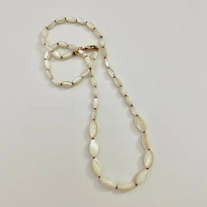 The SANDRINE FRANCE STUDIO - GIANNA NECKLACE features handmade oval white beads, reminiscent of hand-knotted shells, separated by small gold spacers and displayed in a loose curve on a plain white background.