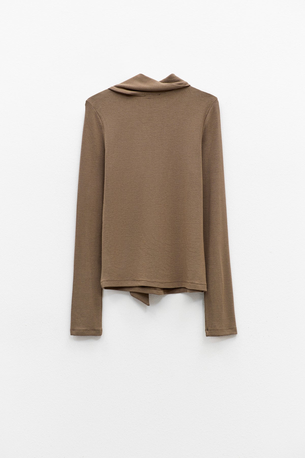 The ELEH - THE SCALA TIE-NECK TOP by ELEH is a light brown, long-sleeved minimalist blouse featuring an asymmetrical attached scarf draped across the front, shown on a hanger against a plain white background.