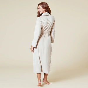 A person wearing a beige SOFTIES - SERENITY WRAP ROBE featuring a wrap silhouette with a tie waist and side pockets.