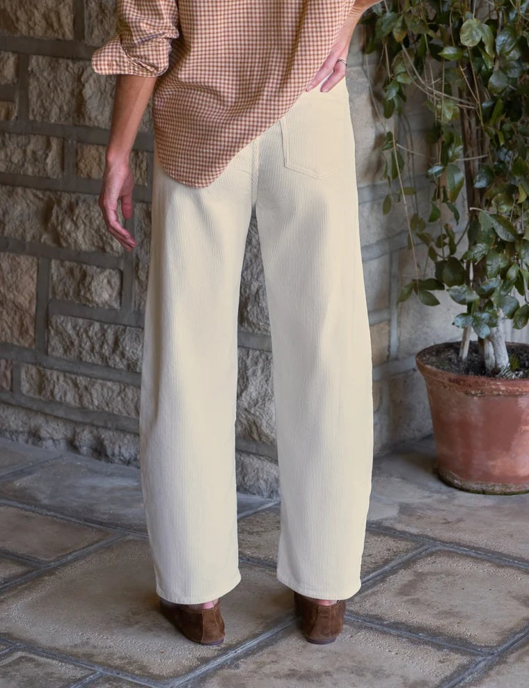 A woman wearing a tan and white gingham button-down shirt tucked into FRANK AND EILEEN - BRENNAN EVERYDAY BARREL IN ITALIAN PERFORMANCE CORDUROY VINTAGE WHITE barrel jeans.