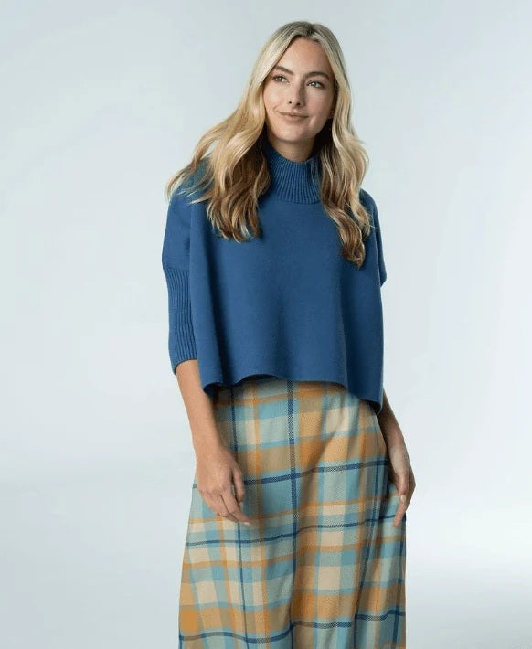 A woman with long blonde hair wears the BRITON COURT - SOPHIA Oversized One Size Sweater in Dusty Navy, standing against a light gray background.