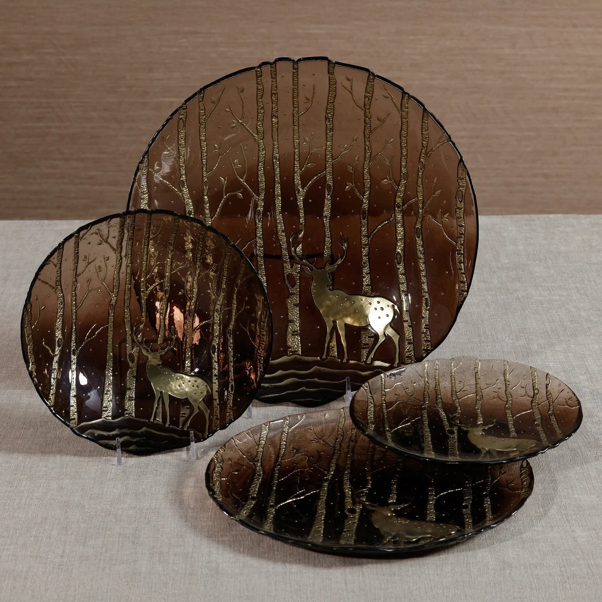 An 8.5-inch translucent brown ZODAX WILDERNESS SERVING BOWL IN TAUPE AND GOLD with a decorative gold forest pattern.