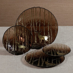 ZODAX WILDERNESS SERVING BOWL IN TAUPE AND GOLD 13″, a round glass serving bowl with a translucent taupe gradient featuring an etched pattern of trees and a deer silhouette in gold.