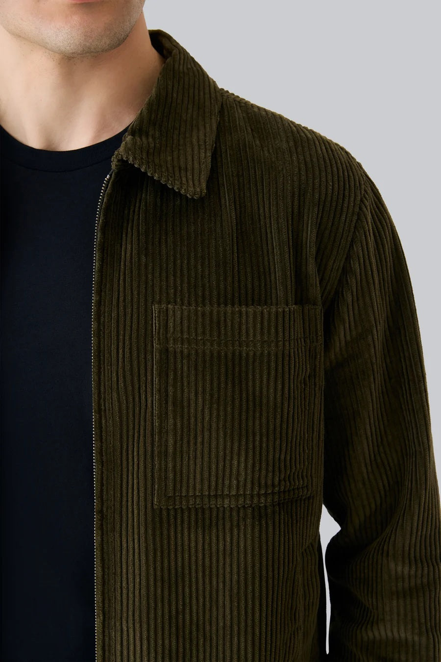 The MACK WELDON - CORDUROY ZIP JACKET is a modern-fit, dark blue corduroy jacket with a front zipper, long sleeves, collar, and chest pocket—shown against a white background.