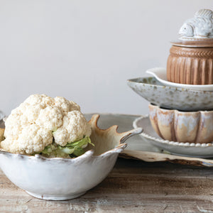 A close-up of the CREATIVE COOP STONEWARE SUNBURST BOWL, a beige ceramic piece with a glossy finish and brown-tinted edges, featuring handcrafted textured details and pointed tips inspired by a leaf’s natural form.