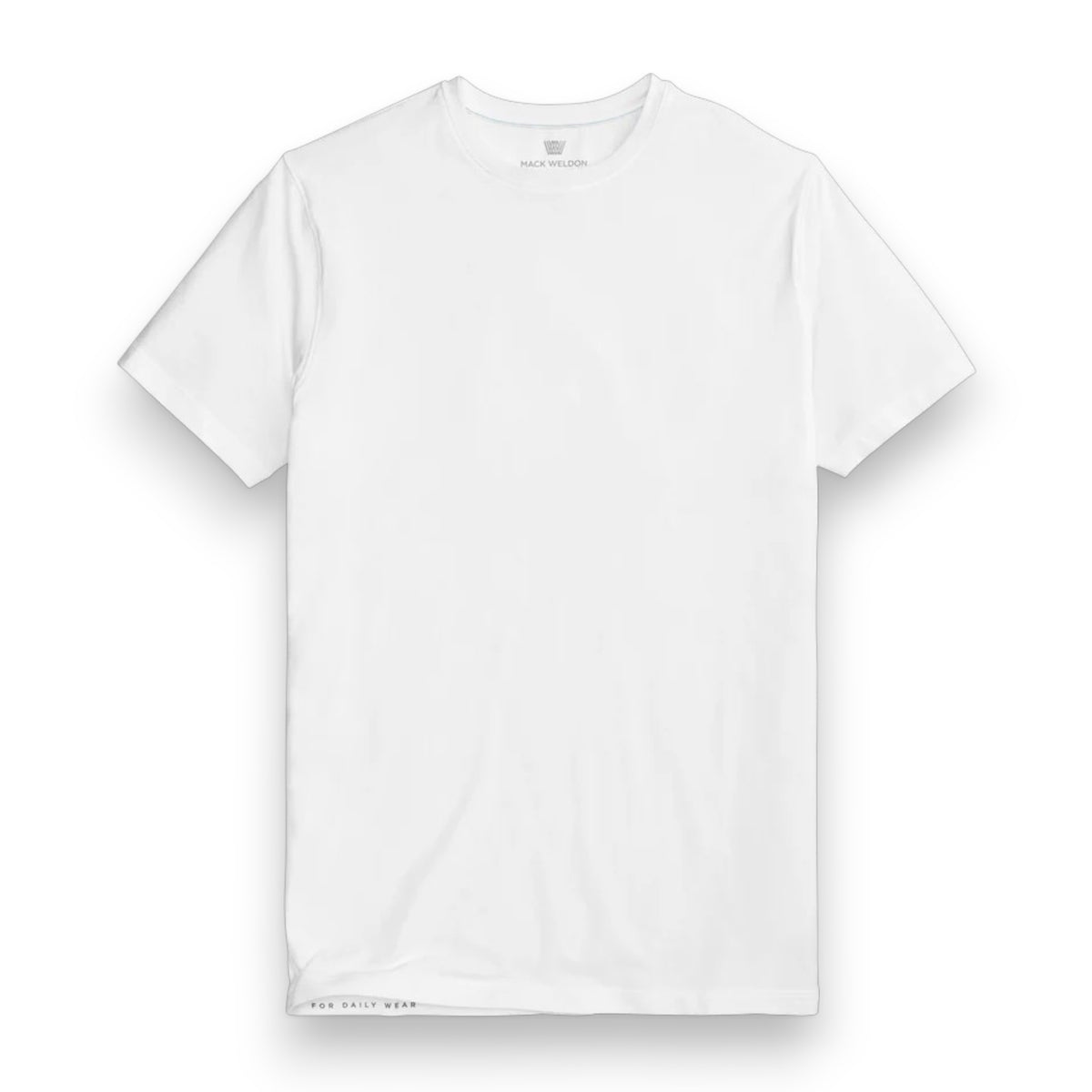 A man with short dark hair and a beard wears the MACK WELDON SILVER CREW NECK T-SHIRT IN WHITE and dark pants, standing in profile with his head slightly bowed and one hand in his pocket against a light gray background.