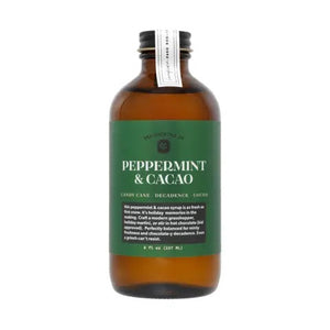 An 8 fl oz brown glass bottle from YES COCKTAIL CO. with a black cap, featuring a green label that reads “PEPPERMINT & CACAO” in white text. The YES COCKTAIL CO. PEPPERMINT & CACAO COCKTAIL SYRUP is an all-natural mixer blending candy cane freshness with decadent cocoa for a festive flavor experience.