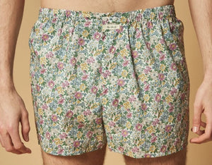 A person stands against a plain background, wearing HARTFORD – COTTON BOXER SHORTS, PATTERN by HARTFORD, featuring a light-colored animal print and crafted from upcycled cotton boxer briefs. Only the lower torso and upper legs are visible.