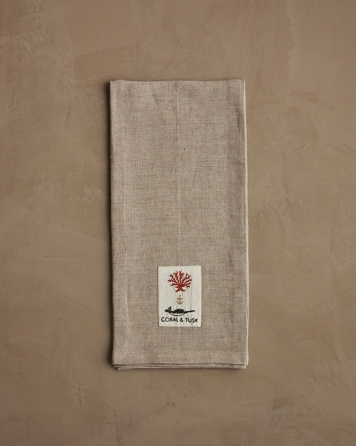 A beige linen DECK THE HALLS FOX LINEN TEA TOWEL embroidered with a fox holding a large, striped Christmas ornament, perfect for vintage Christmas kitchen decor.
