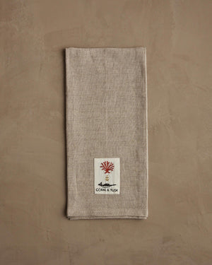 A beige linen DECK THE HALLS FOX LINEN TEA TOWEL embroidered with a fox holding a large, striped Christmas ornament, perfect for vintage Christmas kitchen decor.