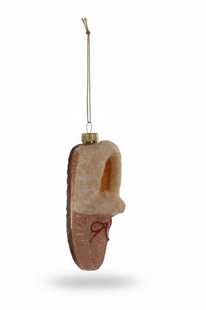 Cody Foster GLASS MOCCASIN ORNAMENT, a 1.5 x 1.5 x 3 inch tan glass moccasin slipper with a glittery finish and a red ribbon bow.