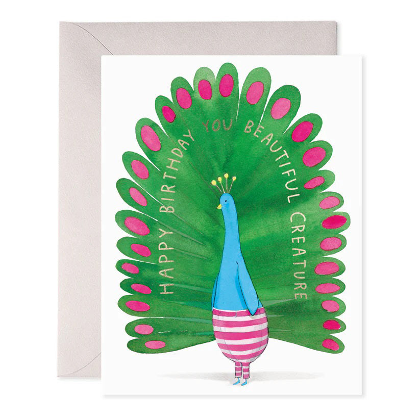 The E. FRANCES PAPER - PEACOCK BIRTHDAY GREETING CARD by E. Frances Paper features a whimsical peacock wearing striped pants and a crown, with green and pink watercolor tail feathers. The card reads "Happy Birthday You Beautiful Creature," with an envelope partly visible behind it.