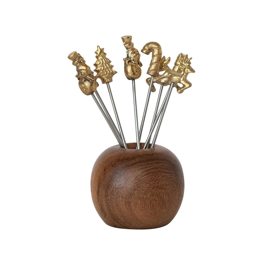 The CREATIVE COOP MANGO WOOD HOLDER WITH APPETIZER PICKS features festive metal picks with snowman, Christmas tree, gift, candy cane, and reindeer handles arranged in a polished round mango wood holder.