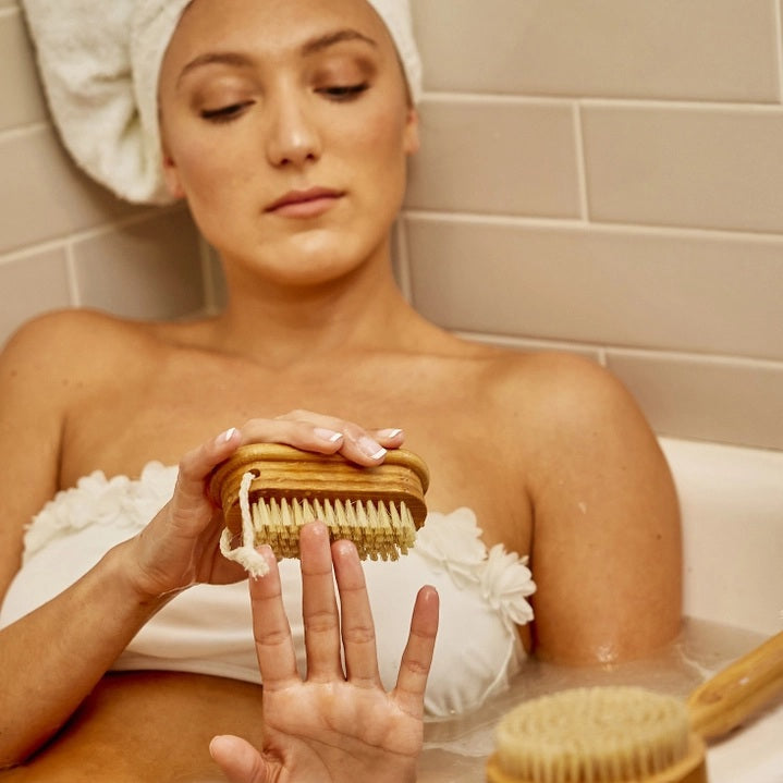 The BAUDELAIRE - BAMBOO 4” NAIL BRUSH by BAUDELAIRE, featuring stiff, light-colored natural boar bristles and a looped rope handle, is displayed on a plain white background.